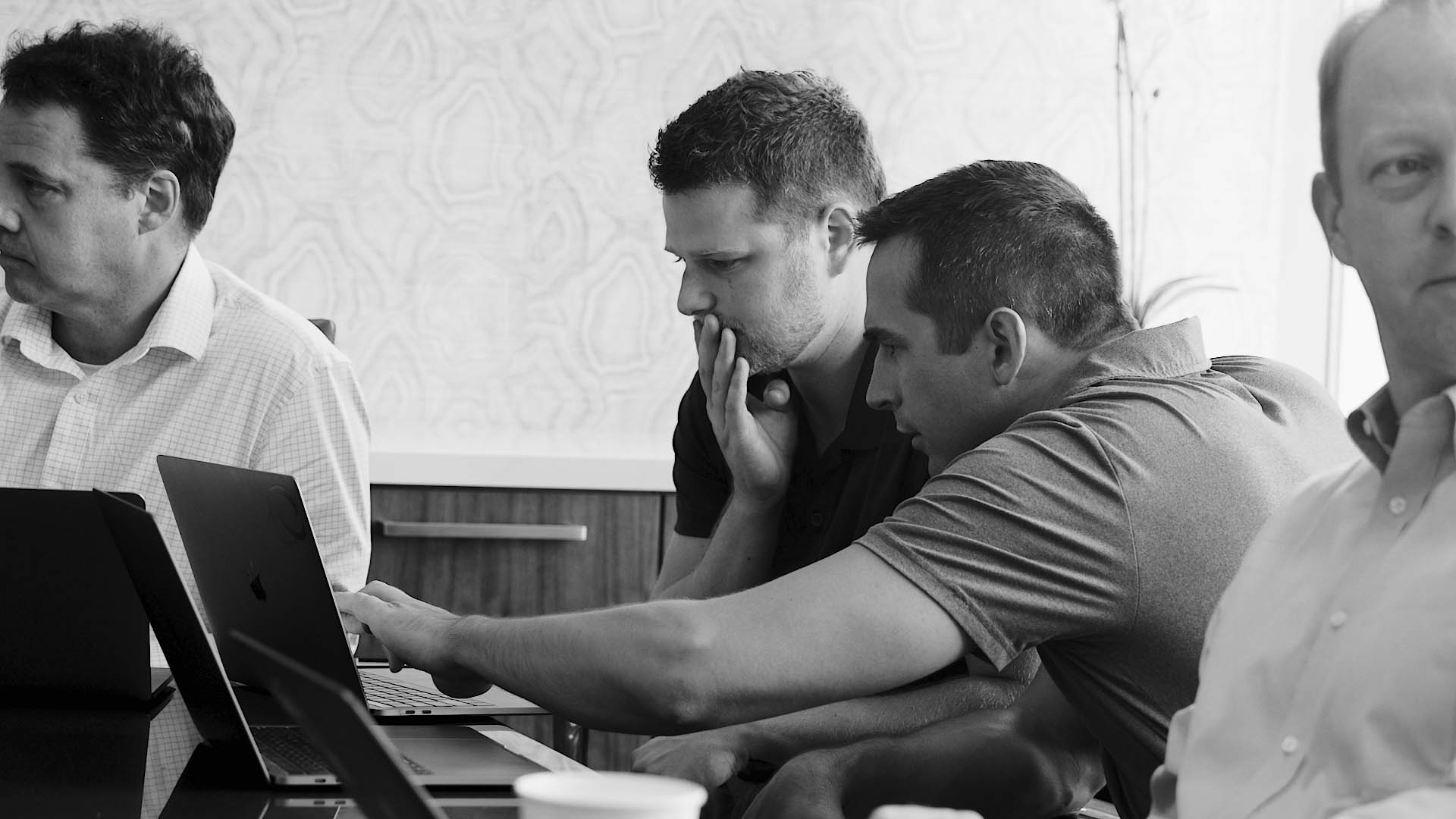 group of men pointing at a computer discussing FinancialForce services