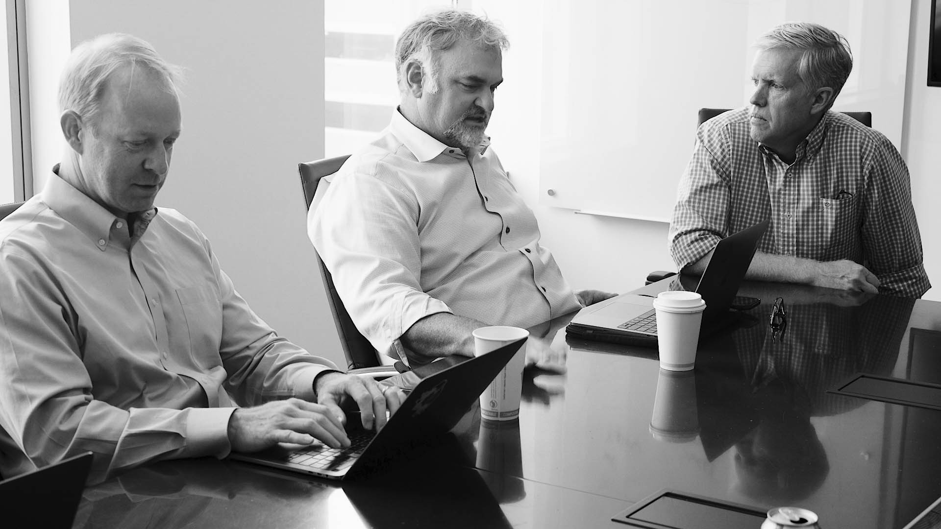 group of men meeting at a conference table discussing ERP implementation solutions