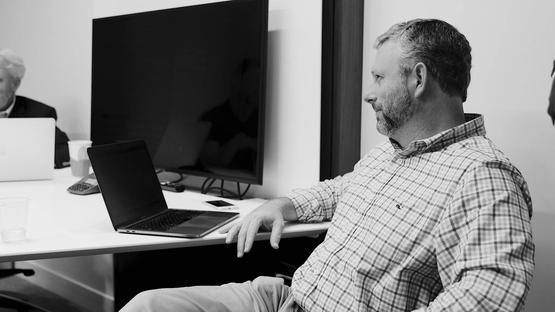 man candidly smiling across a conference table