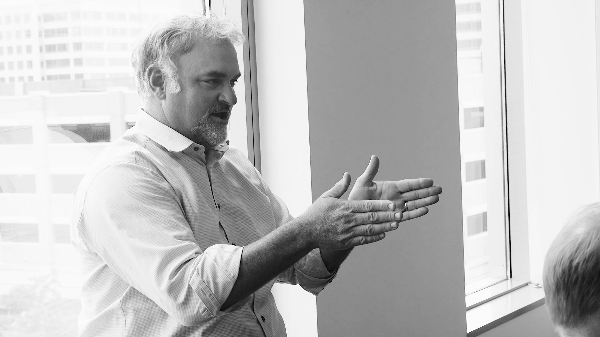 man gesturing with hands at a meeting discussing financialforce erp solutions