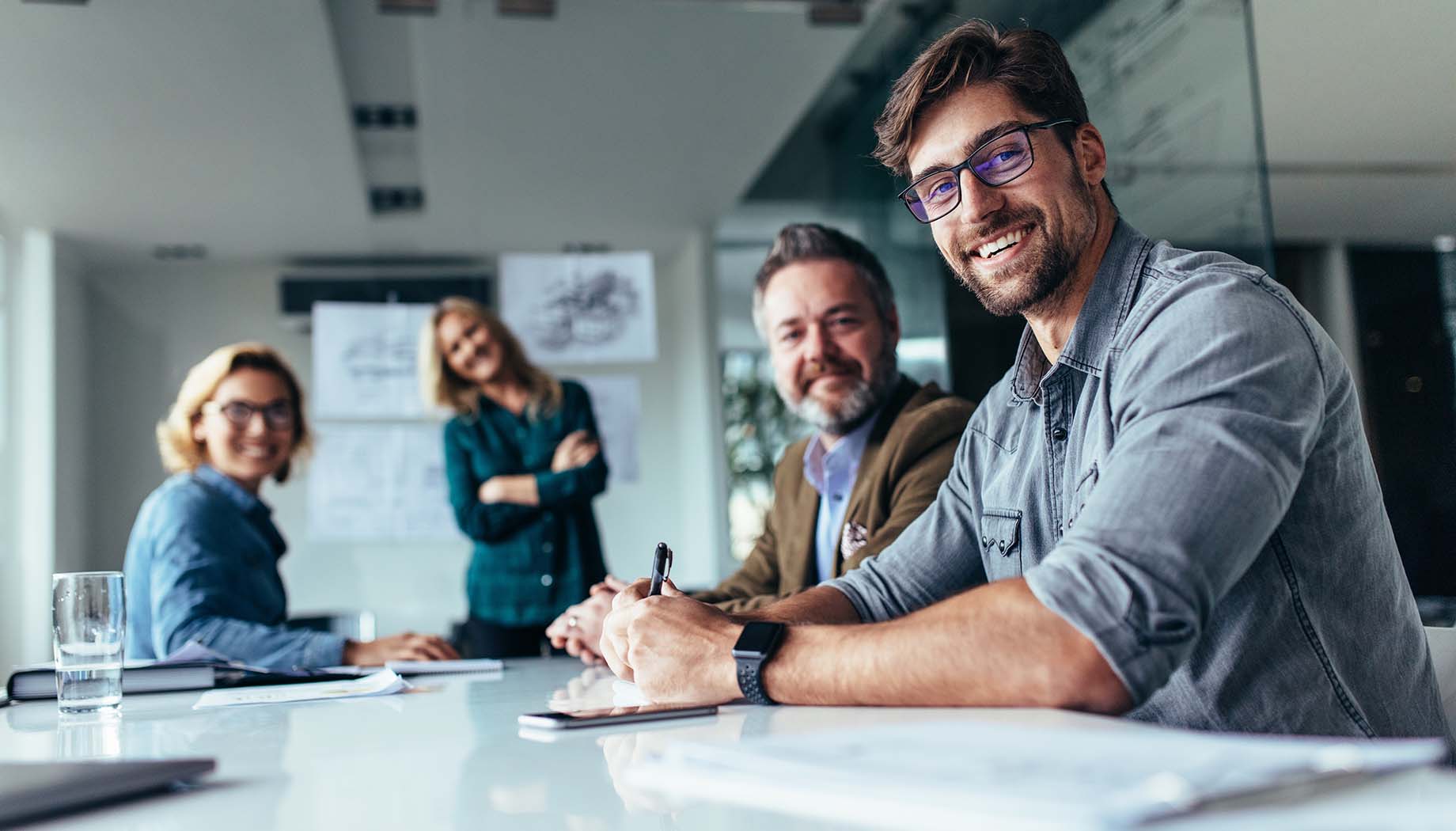 group of men and women working together in office smiling looking at camera
